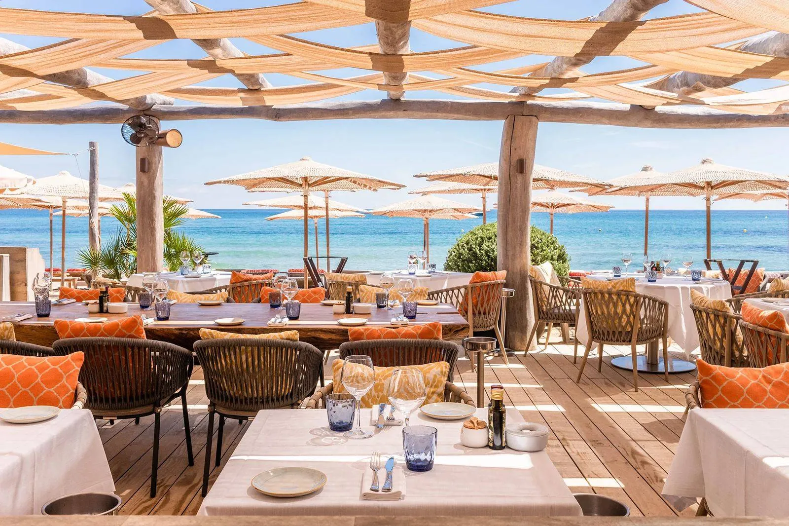 A shaded beach restaurant laid for lunch, facing the sea